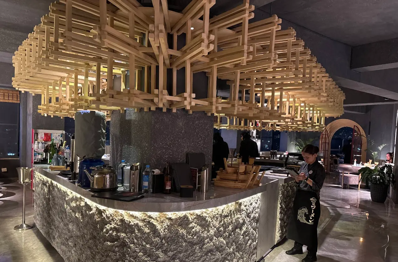 The signature woven-timber lattice canopy suspended above the stone bar at Hokkaido Sora.